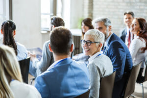 Senior business woman in seminar smiling and talking to colleague